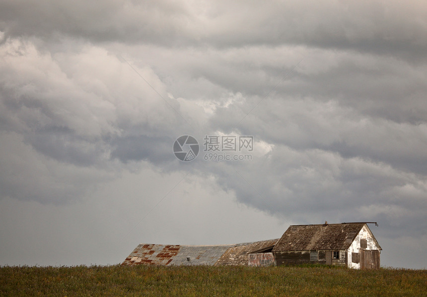 暴风在萨斯喀彻温的一栋旧农庄上飘过水平天空场地乡村房子建筑天气家园植被绿色图片