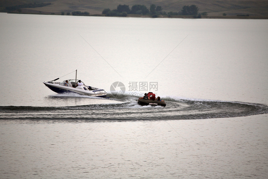 在Diefenbaker湖上拖着木筏的机动艇图片