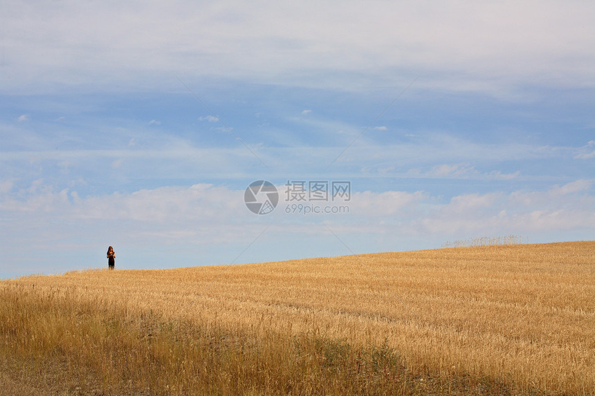 年轻女孩在萨斯喀彻温一个破碎的田间走回来图片
