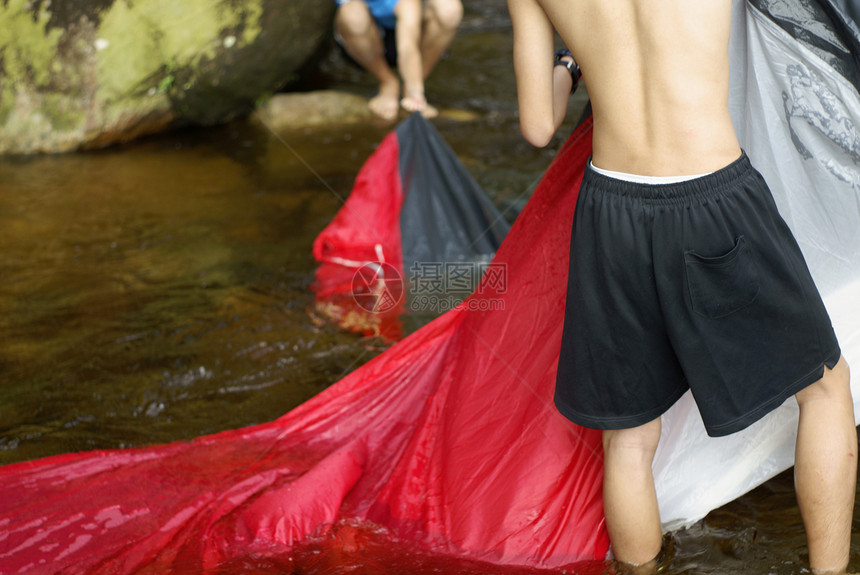 两名亚洲男子在河水中洗红帐篷图片
