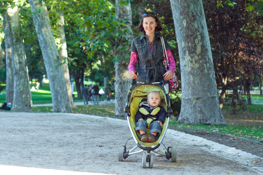 快乐的母亲与她的儿子散步协议衣服活动童年父母闲暇婴儿车公园城市孩子们图片