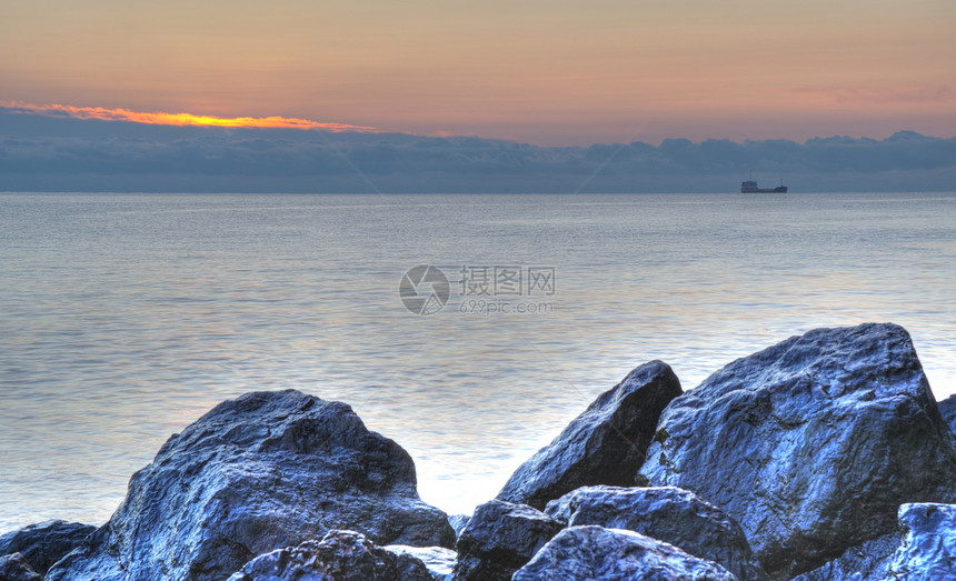 夜间的海岸线和山岳薄雾日落边缘假期卵石阳光风景天空海浪石头图片