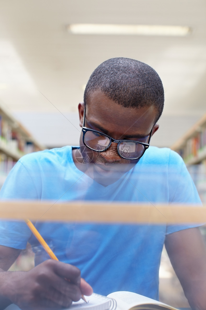 在图书馆学习的非洲青年男子男性专注教育货架铅笔眼镜成人男人沉思桌子图片