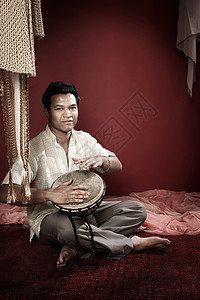 印地安人玩塔普拉音乐家栗色男性手鼓居住音乐窗帘手镯乐器金子背景图片