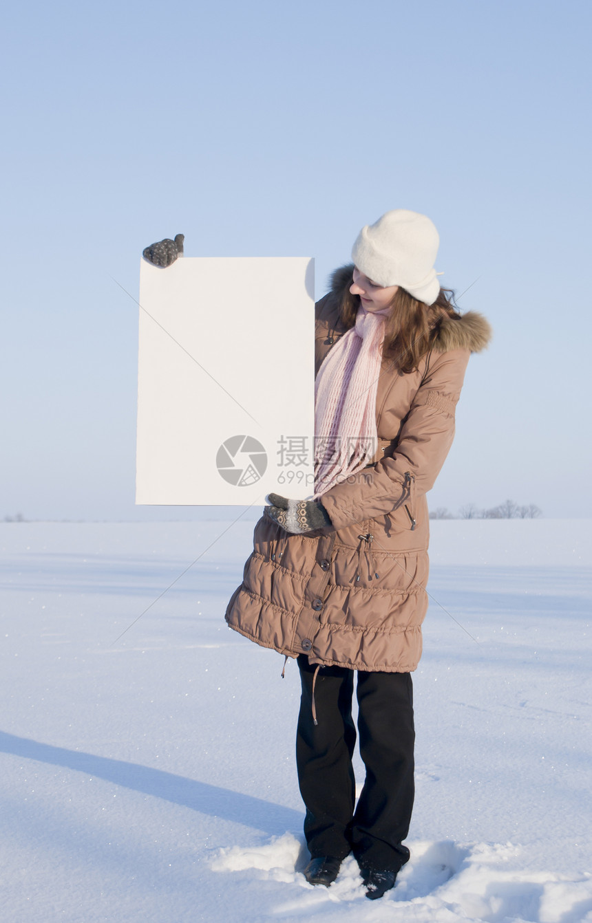女孩在冬季雪田时张贴白海报女性微笑商业广告童年蓝色纸板空白公告横幅图片