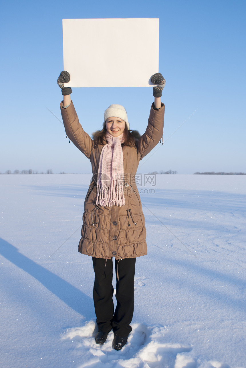 女孩在冬季雪田时张贴白海报快乐场地商业横幅童年孩子纸板女性青少年微笑图片