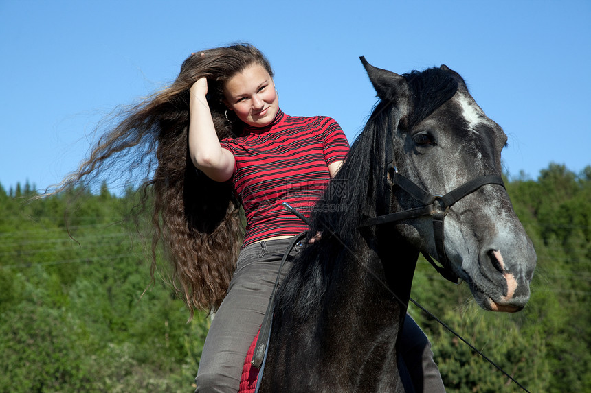 黑马上流着头发的女孩阳光森林训练天空场景运动骑术蓝色马背乡村图片