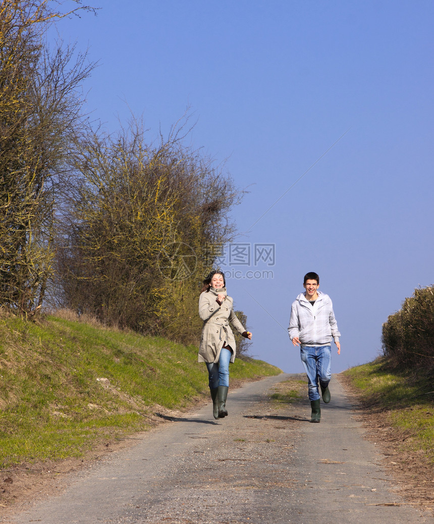 在春季运动中走着一对年轻人的青年天空微笑夫妻青少年蓝色男生跑步笑声民谣友谊图片