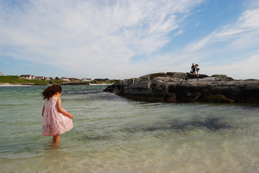 女孩在海中孩子蓝色海洋头发女性海滩天空裙子岩石海岸图片