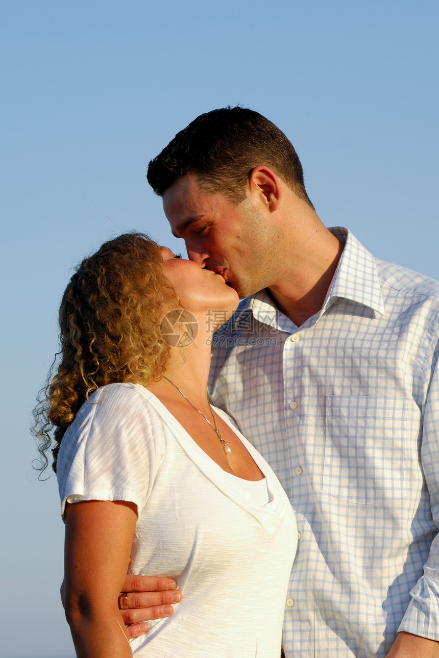 年轻夫妇在接吻拥抱恋人冒充假期喜悦男人男性女孩天空女士图片