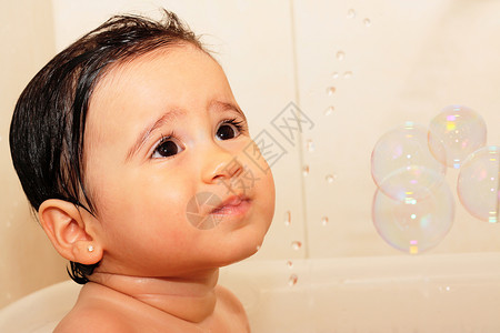 可爱的一岁婴儿在浴室用泡沫玩耍背景图片