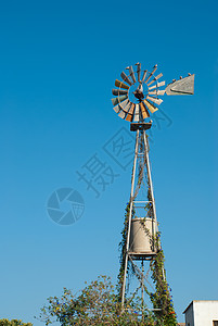 风力泵蓝天农业旋转机器风车杂草古董农场背景图片