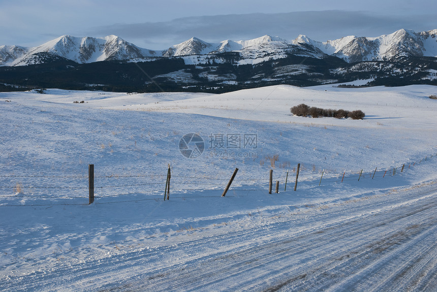 美国蒙大拿州加拉廷县冬季清晨Briger山区山脉 乡村公路和雪雪铺设的牧场图片