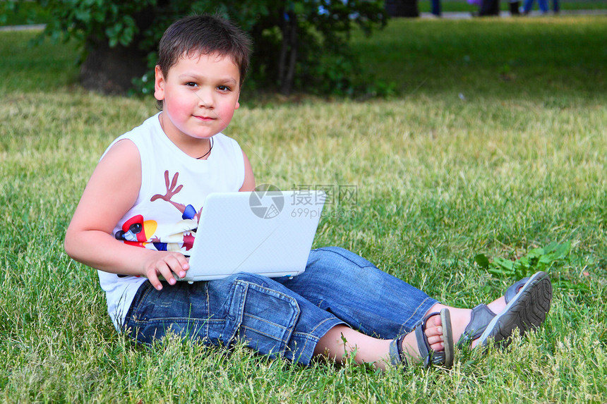 拿着笔记本电脑的小男孩树木专注学校屏幕绿地电子产品男生互联网幸福技术图片
