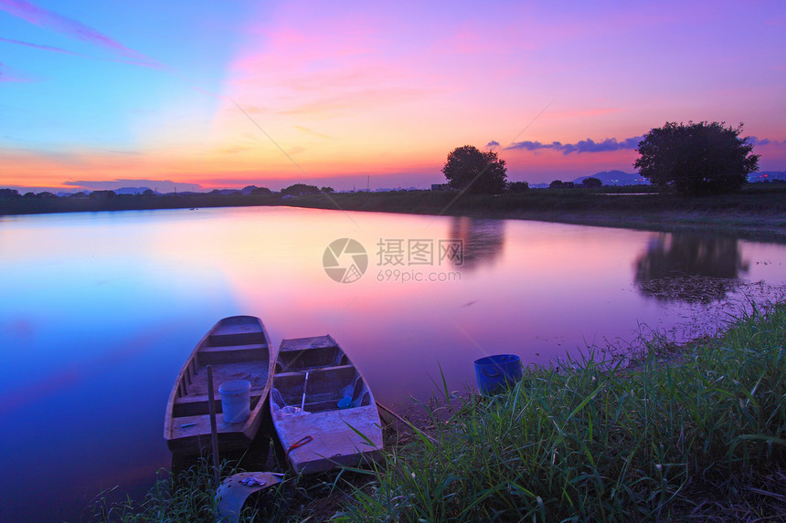 日落时沿池塘的孤立船只图片