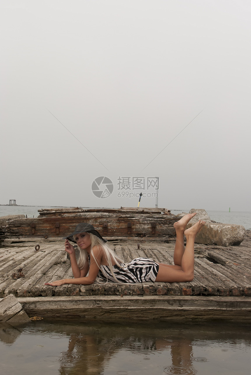身戴帽子的女孩 躺在海上破碎的船上图片