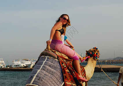 女孩骑着骆驼骑骆驼的妇女;背景