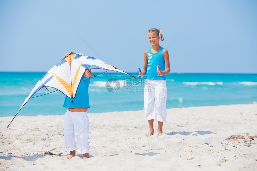 女孩和弟弟在海滩上玩风筝图片