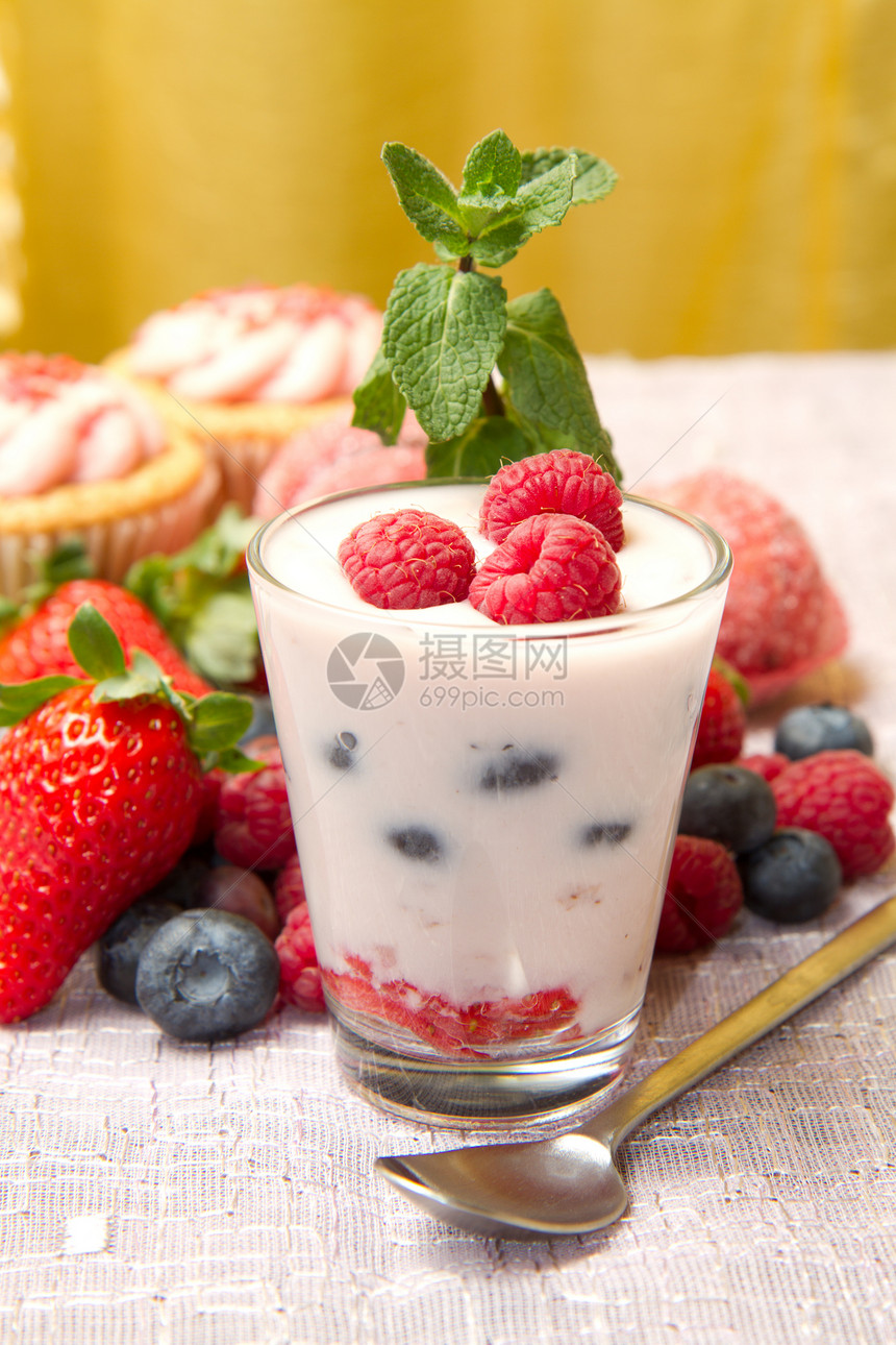 酸奶加浆果和纸杯蛋糕美味粉色营养绿色桌子早餐奶油水果叶子红色图片