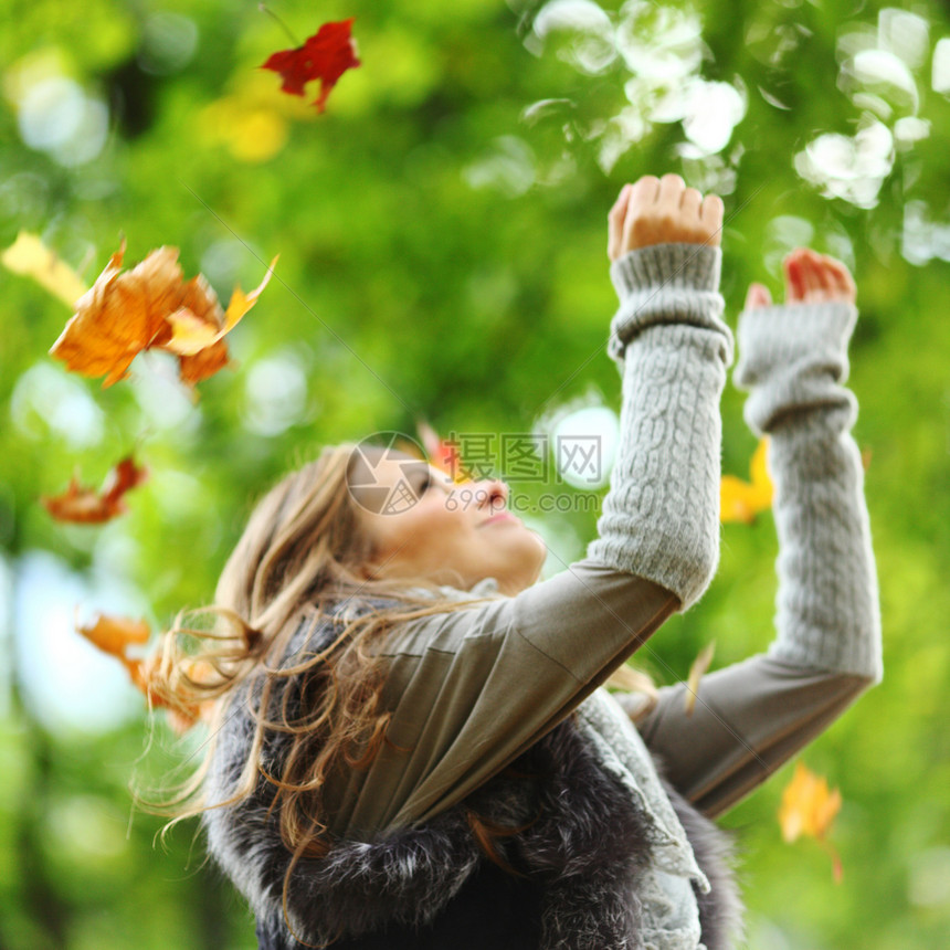 秋天公园的女子落叶木头季节微笑成人幸福快乐公园喜悦假期享受图片