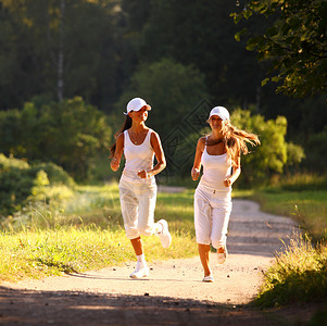 参加竞选的妇女行动公园成人慢跑者火车头发赛跑者运动装女性树木背景图片