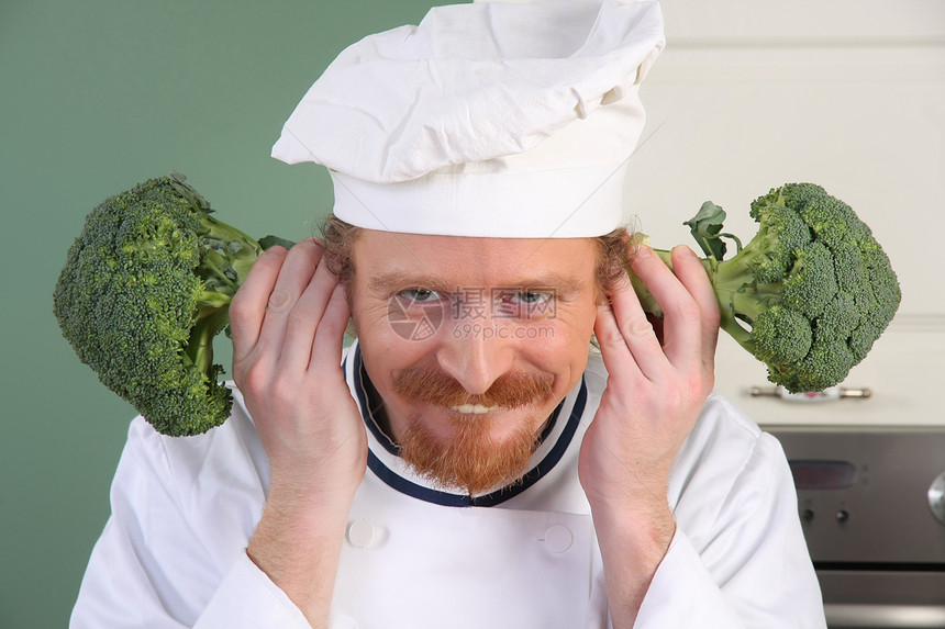带花椰菜的有趣的年轻厨师职业餐具烹饪工人男人厨房烤箱食物衣服白色图片