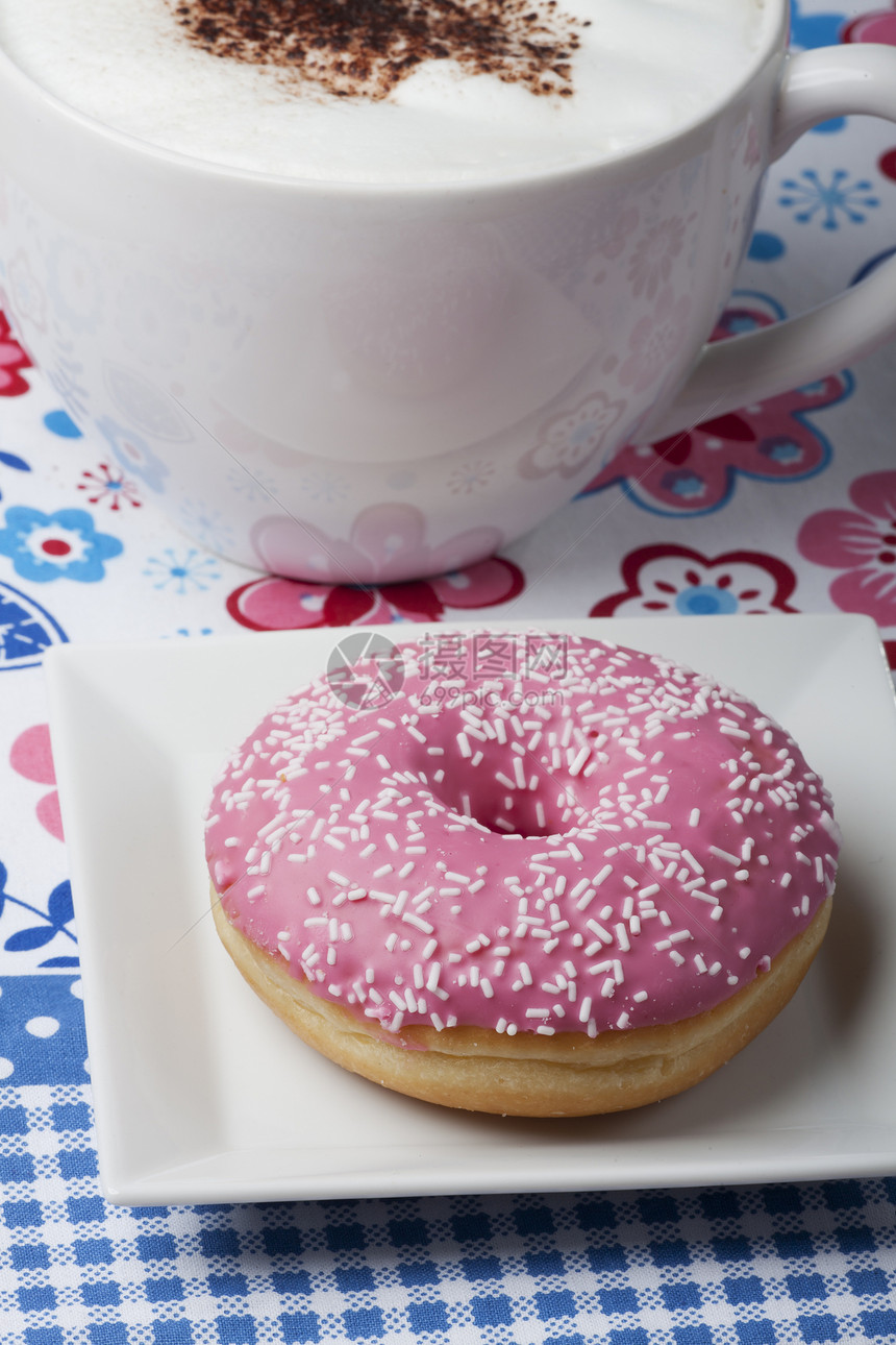 粉红甜甜甜甜圈和一杯卡布奇诺油炸食物面包桌布牛奶蛋糕甜点杯子糕点小吃图片