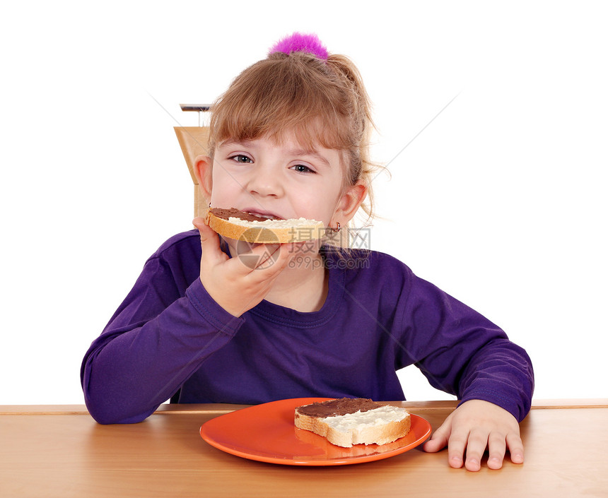 饥饿的小女孩吃面包和巧克力奶油图片