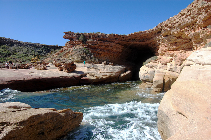 山洞和悬崖岩石蓝天海浪红色洞穴海岸支撑海洋蓝色波浪图片