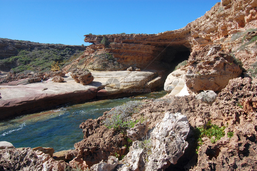 山洞和悬崖洞穴海洋支撑红色蓝天海岸岩石蓝色海浪石头图片