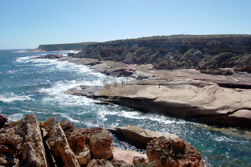 海岸的岩石蓝色海洋波浪支撑悬崖红色石头蓝天海浪图片