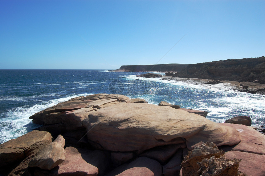 海岸的岩石支撑蓝天波浪海浪红色石头蓝色海洋悬崖图片