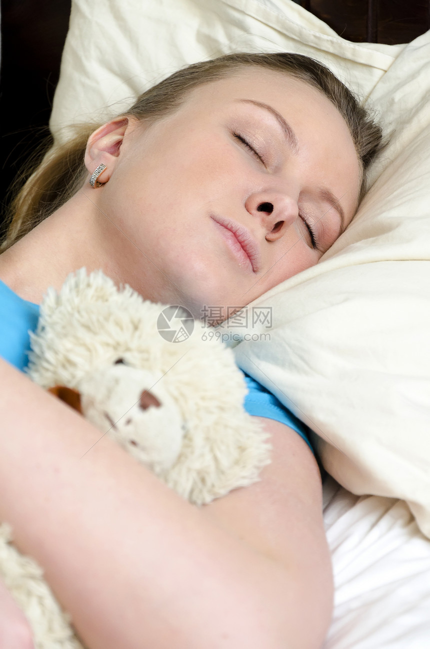 年轻女孩和泰迪熊睡着说谎卧室睡眠童年枕头就寝时间眼睛软垫蓝色图片