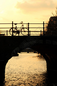 荷兰自行车日落时在阿姆斯特丹运河上背景