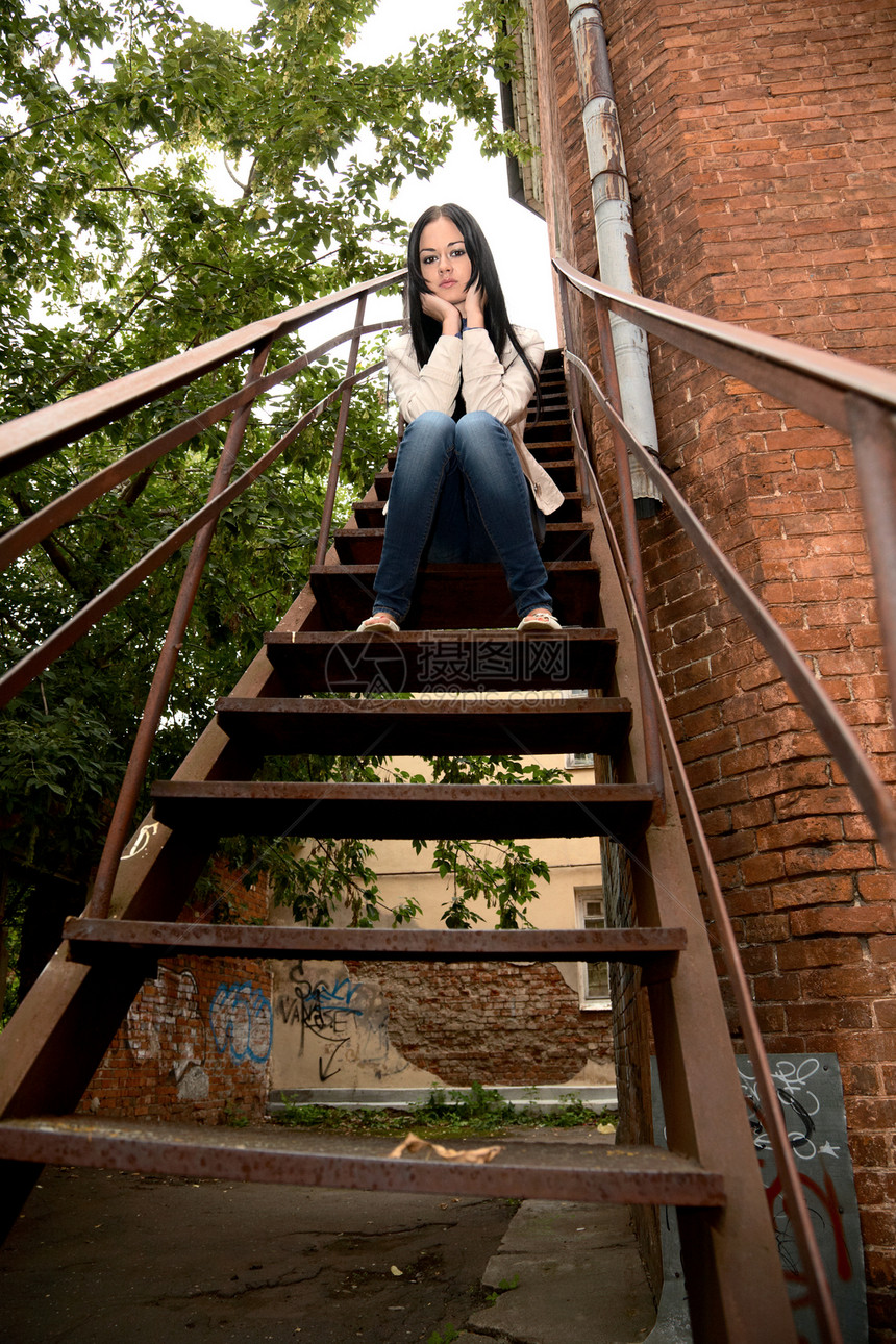 女孩坐在房子的铁梯子上图片