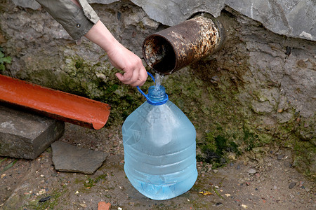 临界点女性手握着装有水的塑料瓶流动地下水塑料环境苔藓尾巴生态来源卵石气泡背景