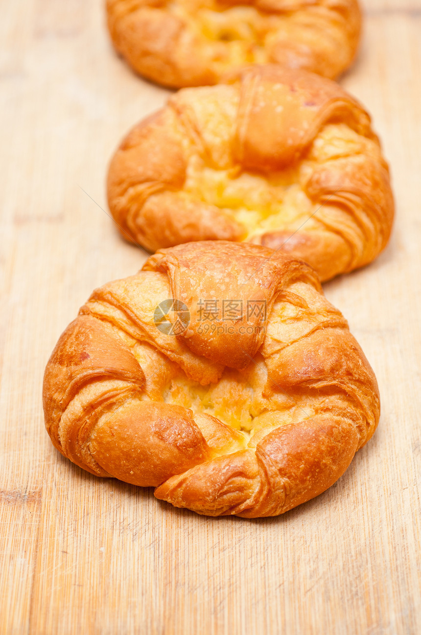 木板上新鲜烘烤的法国牛角面包脆皮羊角面团糕点黄油盘子新月包子金子甜点图片