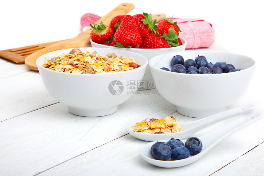 白色瓷砖B中的新鲜蓝莓 草莓和玉米薄片水果勺子餐巾纸红色桌子早餐蓝色食物饮食玉米片图片