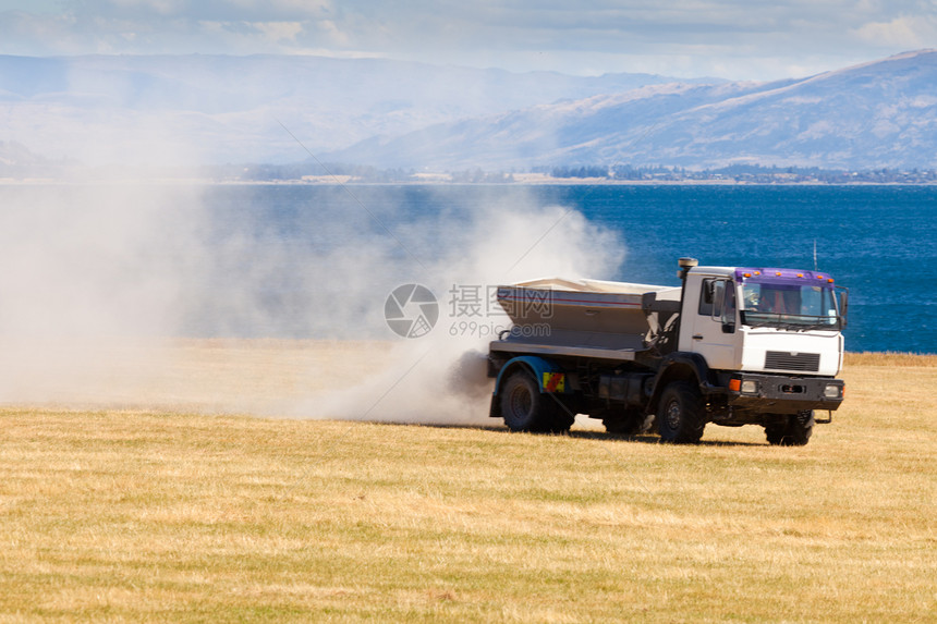 在牧场草原上撒肥的卡车吊具农场土地喷涂草地灰尘环境施肥农田治疗图片