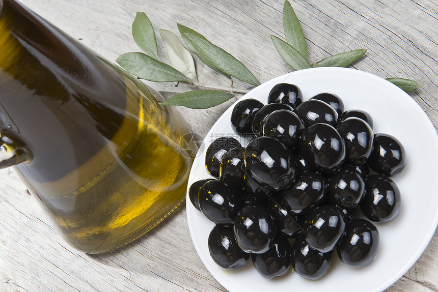 橄榄油和黑色橄榄的盘子玻璃收成营养美食调味品商业饮食烹饪瓶子木头图片