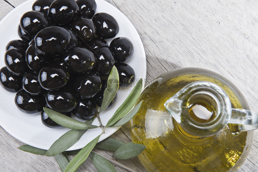 橄榄油和黑色橄榄的盘子玻璃营养处女营销调味品蔬菜水果木头瓶子叶子图片
