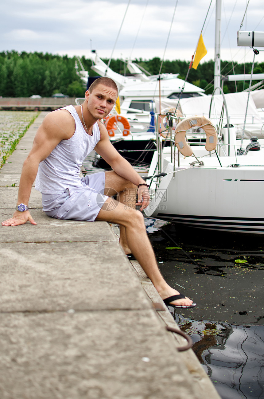 坐在游艇附近的有吸引力的肌肉男性图片