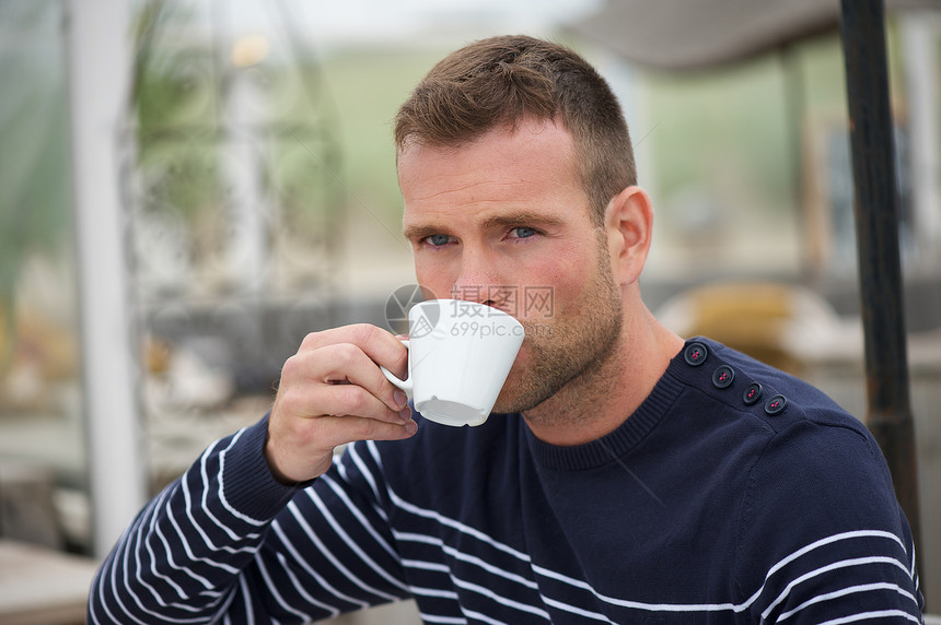 年轻人在沙滩喝咖啡成人太阳饮料咖啡男人海洋蓝色香气咖啡店假期图片