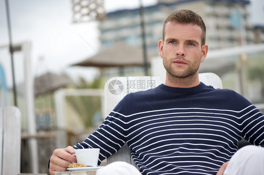 年轻人在沙滩喝咖啡休息室蓝色成人海岸海滩海洋毛衣杯子饮料早餐图片