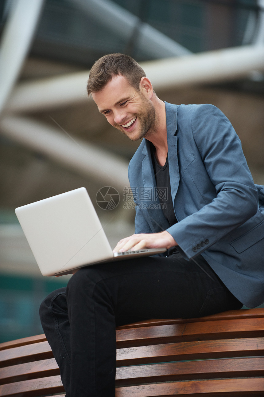 年轻人和笔记本电脑坐在一起互联网公园男性座位闲暇享受冲浪网络微笑幸福图片