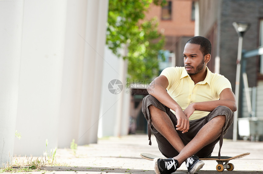 坐在滑板上的年轻黑男性图片