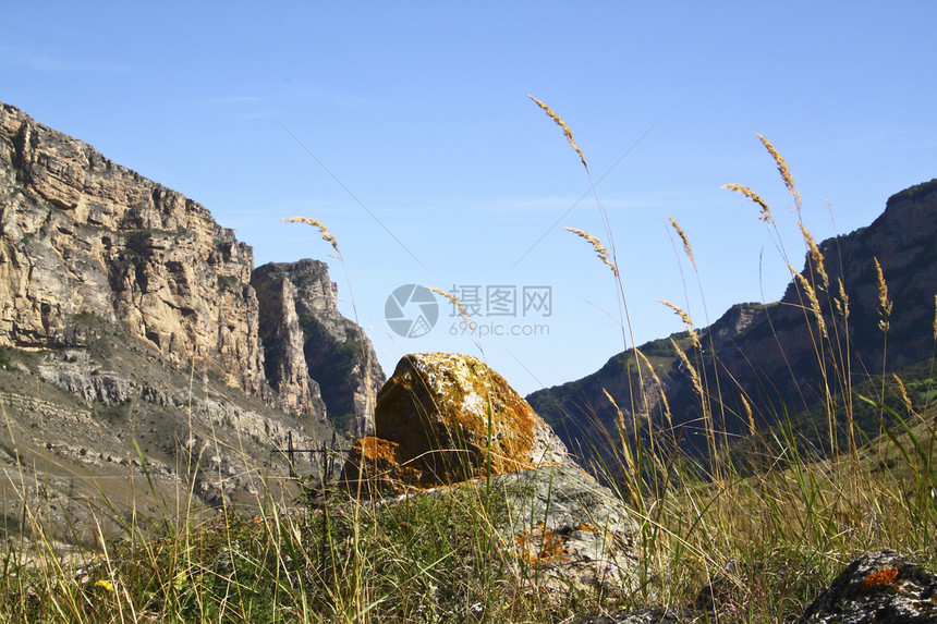 在背景天空和山顶的石头灰色黄色苔藓岩石蓝色白色黑色图片