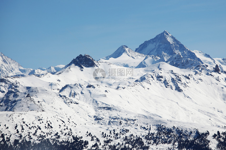 山上有高山暴风雪滑雪全景云杉小路太阳蓝色旅行松树顶峰图片
