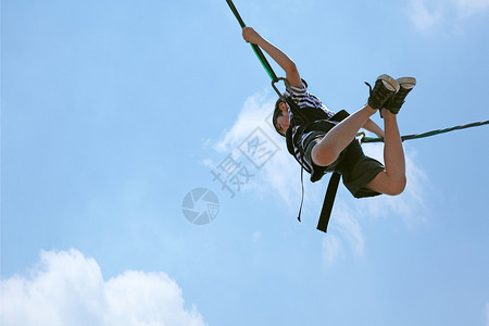 Bungee 跳球男孩对抗蓝云天空和滑过路径背景