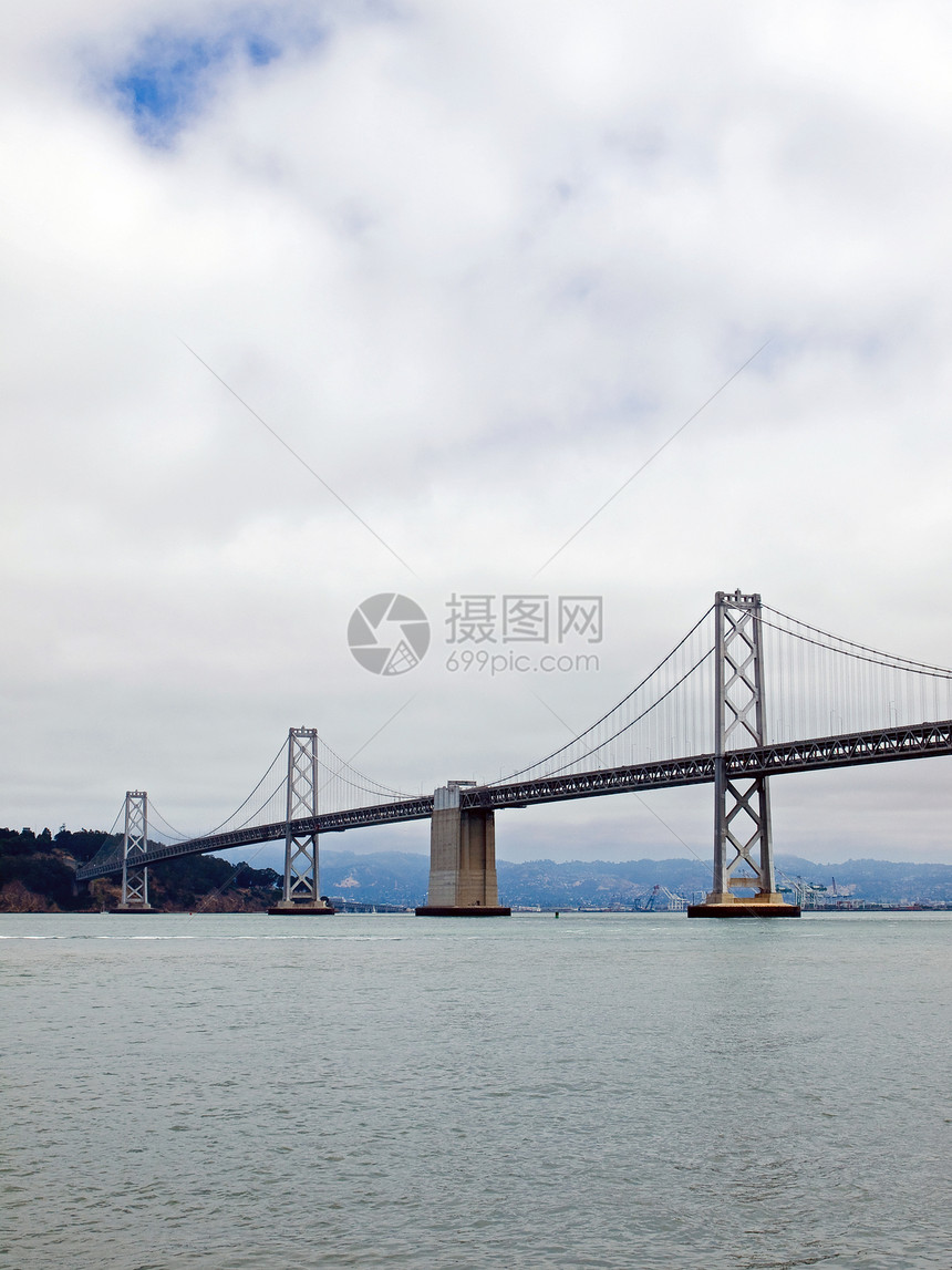 旧金山湾大桥在云天建筑工程城市旅行电缆历史性运输水路地标天空图片